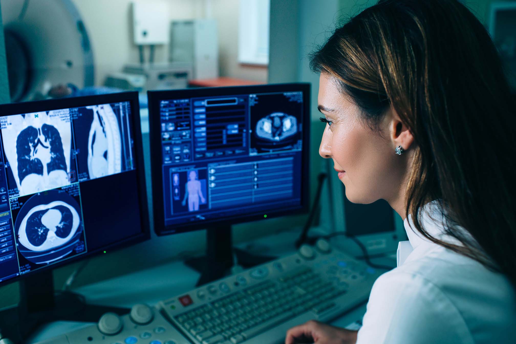 Female doctor running CT scan from control room at hospital